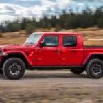 A red 2020 Jeep Gladiator is driving past a blurred field after winning the 2020 Jeep Gladiator vs 2020 Ford Ranger comparison.