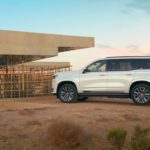 A white 2021 Cadillac Escalade is parked in front of a modern home in the desert.