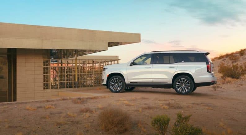 A white 2021 Cadillac Escalade is parked in front of a modern home in the desert.