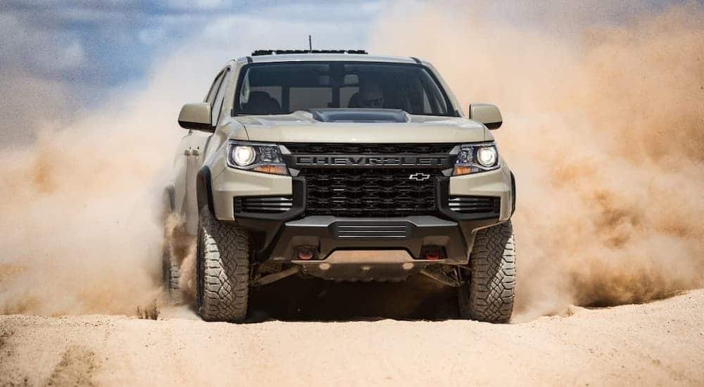 A tan 2021 Chevy Colorado is kicking up sand.