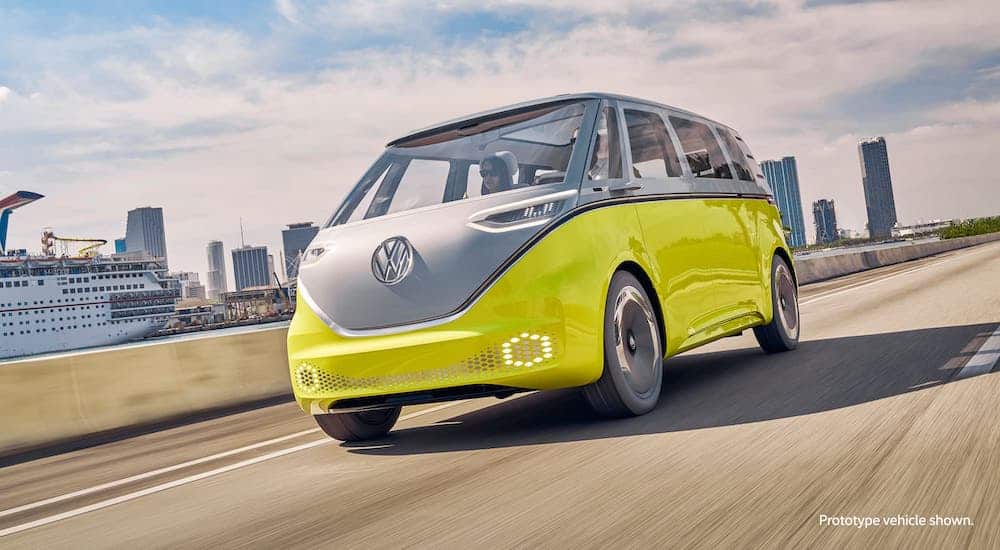 A blue and white 2022 VW Microbus prototype is driving on a highway.