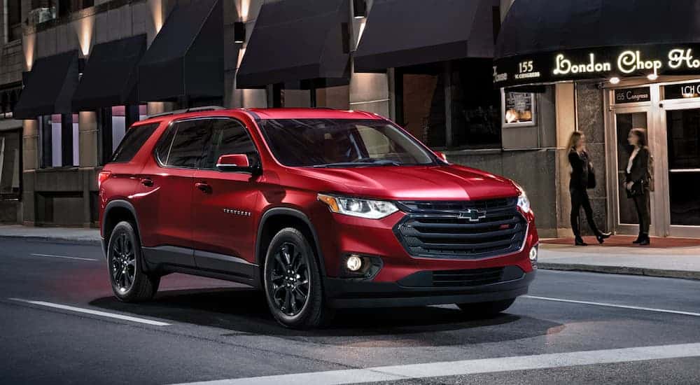 A red 2020 Chevy Traverse is stopped at a city intersection at night.