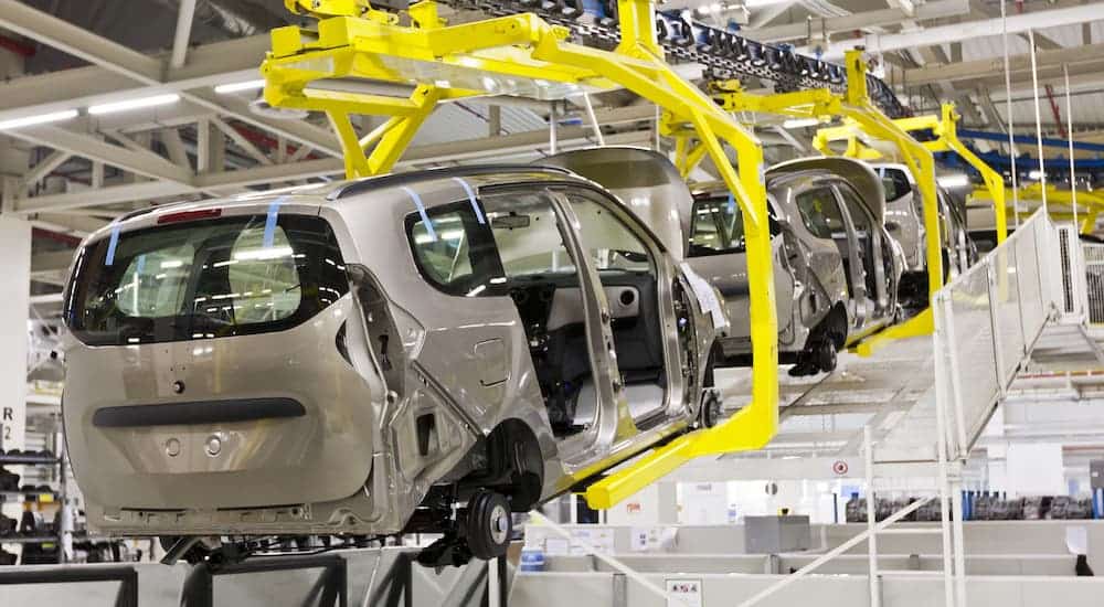 A row of cars are shown in an empty factory.
