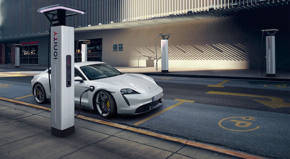 A white Porsche Taycan is charging at a charging station.