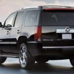 A black 2012 pre-owned Cadillac Escalade is shown from the rear with clouds in the background.