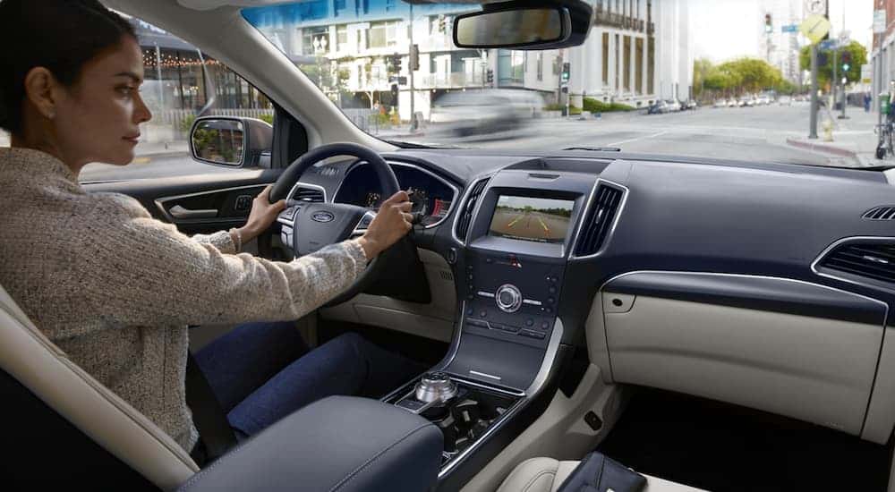 A woman is using the backup camera in a 2020 Ford Edge in a city.