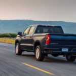 A blue 2020 Chevy Silverado 1500, which is popular among trucks for sale, is driving toward mountains.