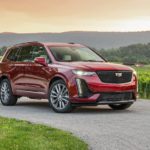 A red 2020 Cadillac XT6 Sport is parked in front of a vineyard at sunset.
