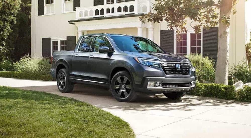 A gray 2020 Honda Ridgeline RTL-E is parked in front of an upscale home.