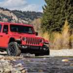 A red 2020 Jeep Gladiator Rubicon with a hard top is shown crossing a river.