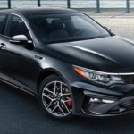 A grey 2020 Kia Optima is parked on a pier in front of water after winning the 2020 Kia Optima vs 2020 Nissan Altima comparison.