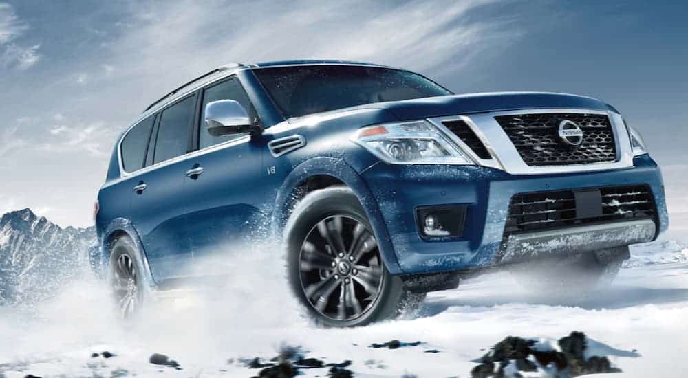 A blue 2020 Nissan Armada is driving in the snow.