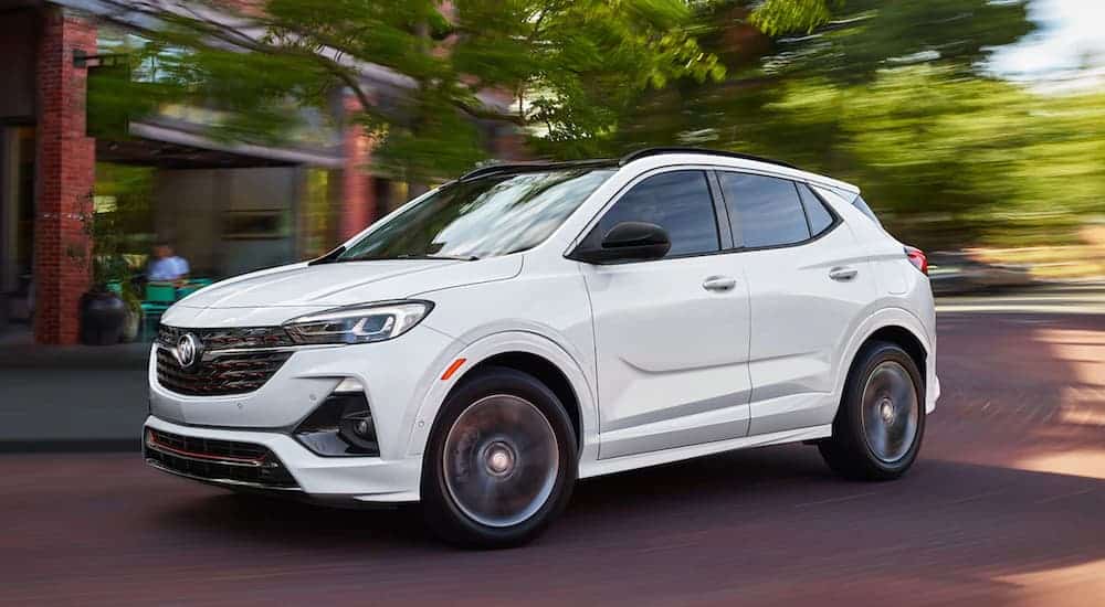A white 2020 Buick Encore GX is racing around a corner downtown.