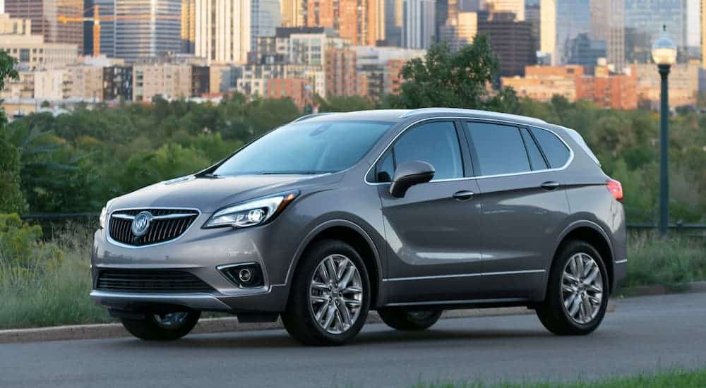A grey 2020 Buick Envision is parked in front of city buildings.