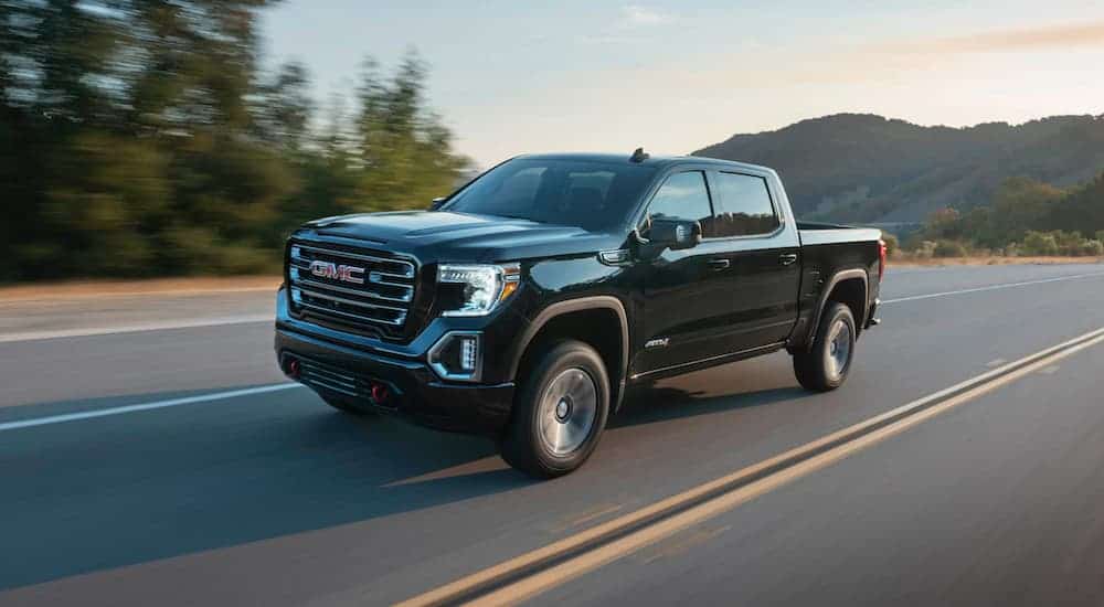 A black 2020 GMC Sierra 1500 AT4 is driving away from mountains after leaving a GMC dealer.
