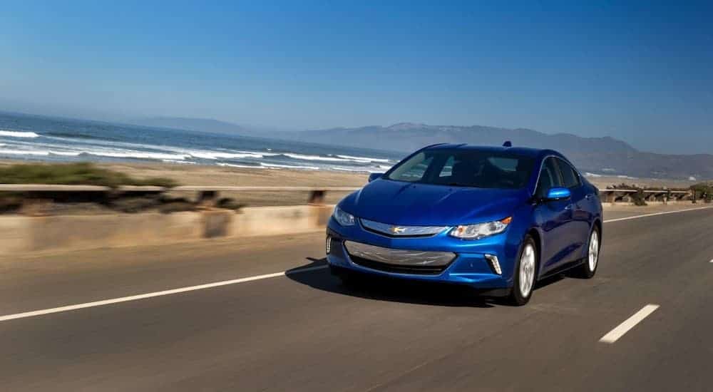 A blue 2018 used Chevrolet Volt is driving past the ocean.