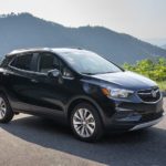 A black 2020 Buick Encore is parked in an empty lot with hills in the distance after being part of the 2020 Buick Encore comparison.