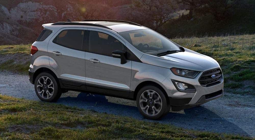 A silver 2020 Ford EcoSport is on a narrow road with a sun flare above.