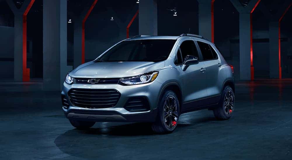 A silver 2020 Chevy Trax is in a dark showroom.