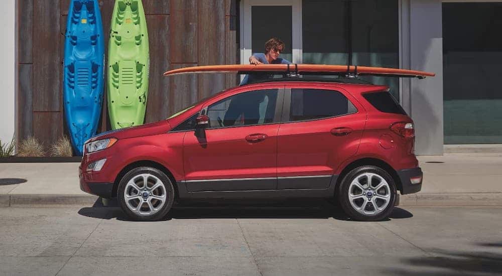 A red 2020 EcoSport with surfboards on the roof rack is shown from the side after winning the 2020 Ford EcoSport vs 2020 Nissan Kicks comparison.