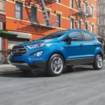 A blue 2020 Ford EcoSport is driving on a city street.