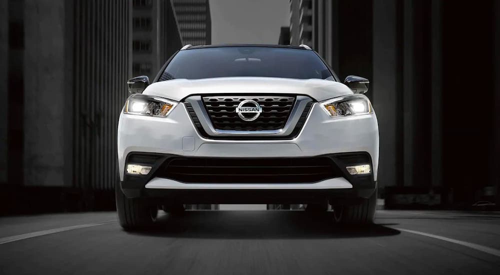 A white 2020 Nissan Kicks is shown from the front in a city alley.