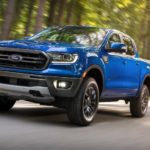 A blue 2020 Ford Ranger is driving on a tree-lined road.