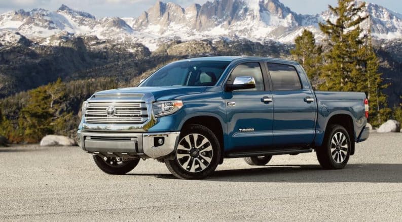 A blue 2020 Toyota Tundra is parked in a parking lot in front of snowy mountains.