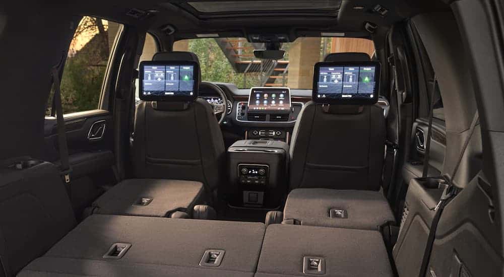 The rear seats in a 2021 Chevy Tahoe are folded down to show the infotainment features.