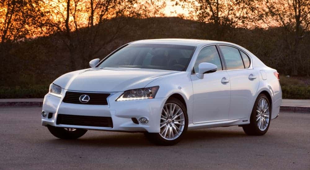A white 2015 Lexus GS is parked in front of tress at sunset.