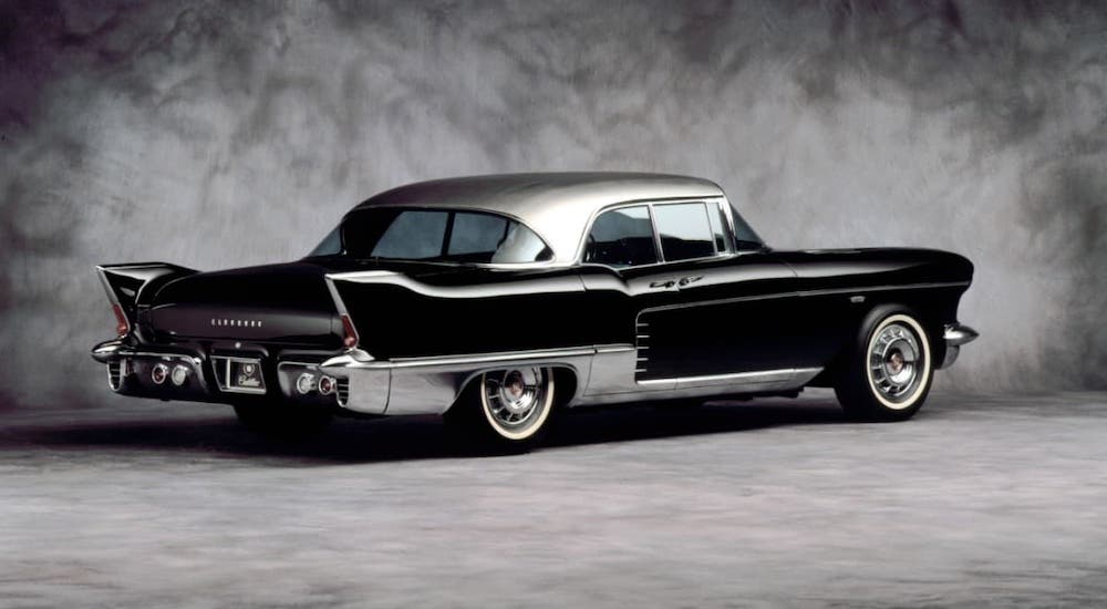 One of the classic used luxury cars, a black 1957 Cadillac Eldorado Brougham is parked against a gray textured background.