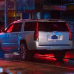 A silver 2020 Cadillac Escalade ESV is parked on a city street at night.