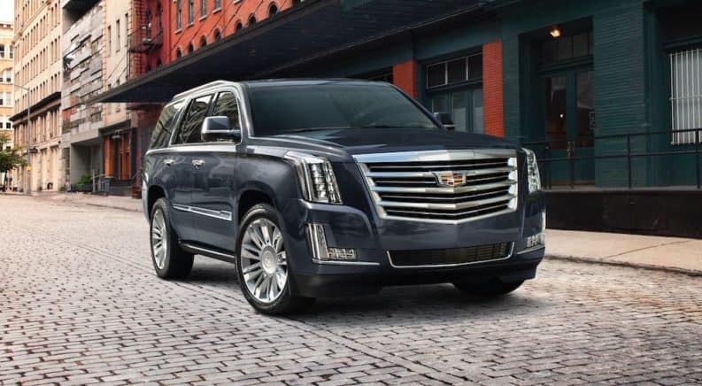 A dark blue 2020 Cadillac Escalade is parked on a cobblestone city street.