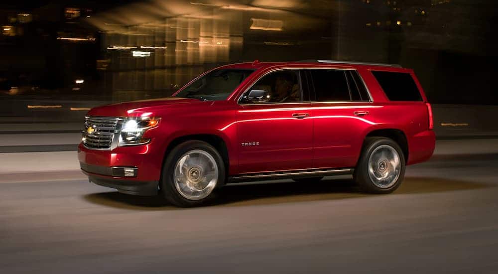 A red 2020 Chevy Tahoe is driving on a city street at night.
