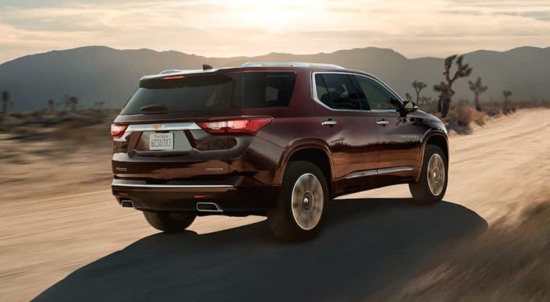 A burgundy 2020 Chevy Traverse is driving on a dirt road in the desert after winning the 2020 Chevy Traverse vs 2020 Ford Explorer comparison.