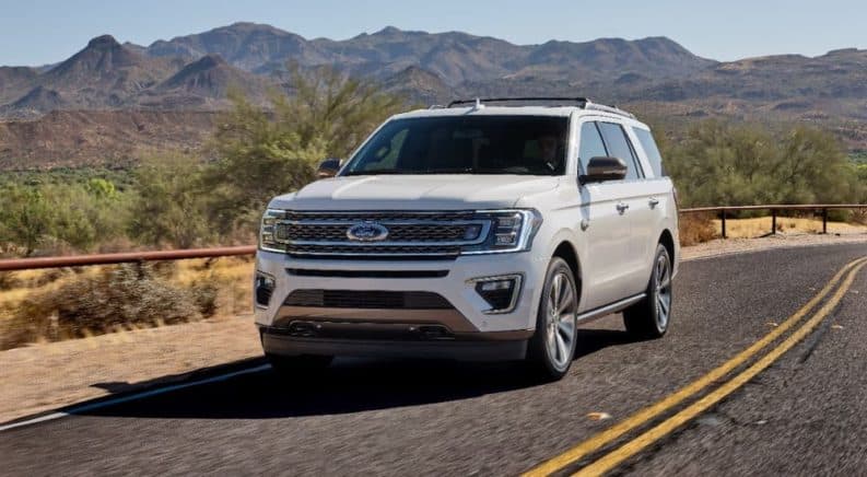 A white 2020 Ford Expedition King Ranch is driving on a desert highway.
