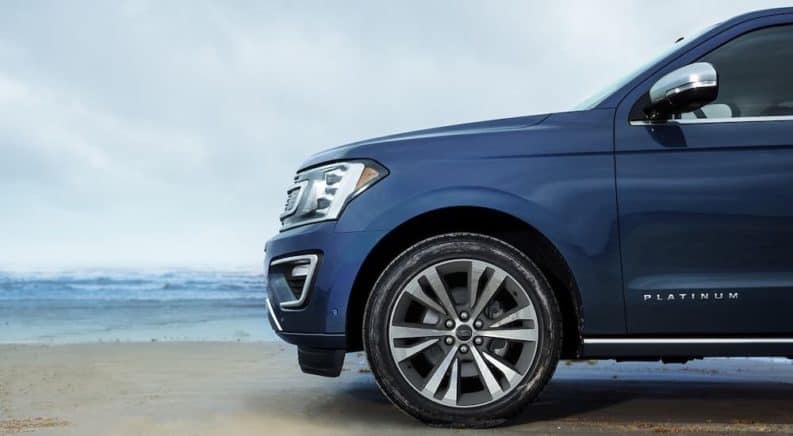 The front half of a blue 2020 Ford Expedition Platinum is shown from the side while parked at a beach.