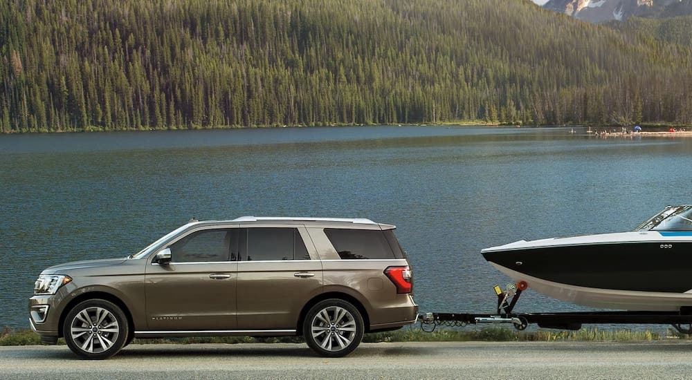 A gray 2020 Ford Expedition Platinum is shown from the side towing a boat in front of a lake after winning the 2020 Ford Expedition vs 2020 Chevy Tahoe comparison.