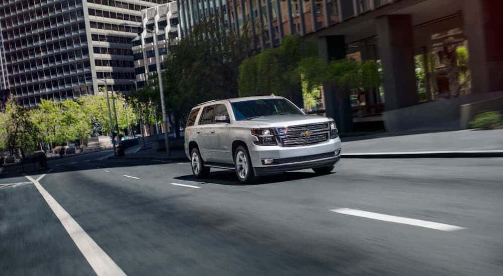 A silver 2020 Chevy Tahoe is driving on a city street.