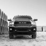 A black and white photo shows a black 2020 Ram 2500 from the front next to concrete tubes.
