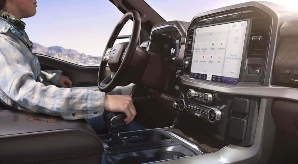 The infotainment screen is shown while someone is driving a 2021 Ford F-150.