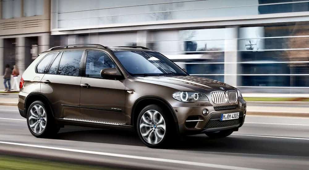A brown 2020 BMW X5 is driving on a city street.