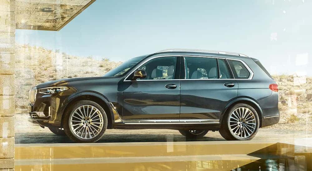 A grey 2020 BMW X7 is parked outside a desert home.