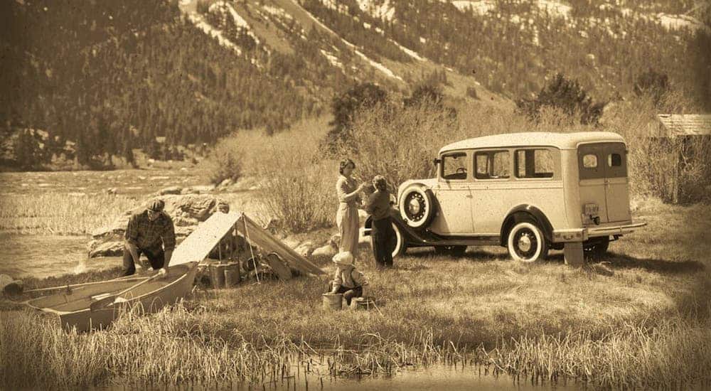 A vintage sepia-tones picture shows a family setting up camp next to their 1935 Chevy Suburban.