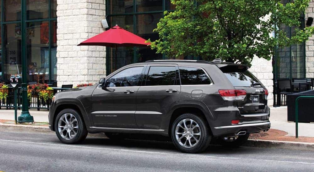 A gray 2020 Jeep Grand Cherokee is parked in front of an outdoor restauruant.
