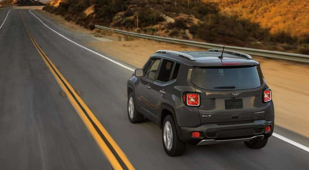 A gray 2020 Jeep Renegade is driving away on an empty highway.