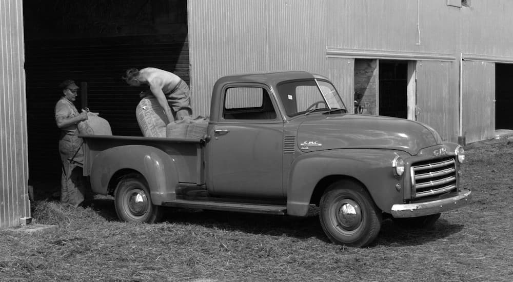 Men are loading the bed of a 1948 GMC FC101 Half Ton, a rare truck for sale, shown in black and white.