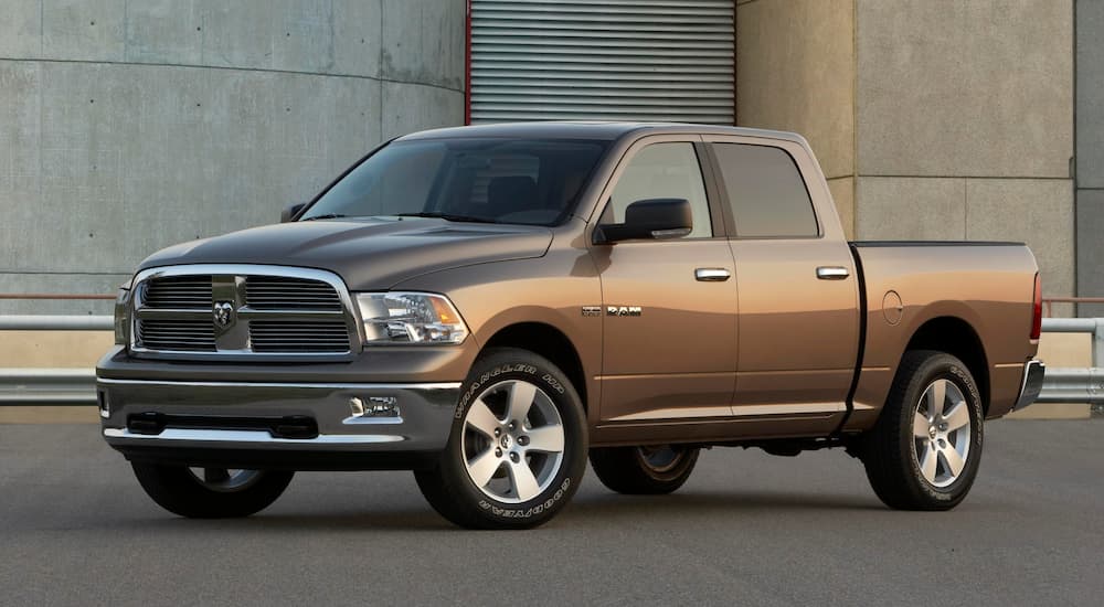 A brown 2009 used Ram 1500 is parked in front of an industrial building.