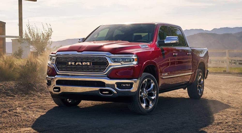 A red 2019 used Ram 1500 is parked in front of a fence and mountains on a dirt road.