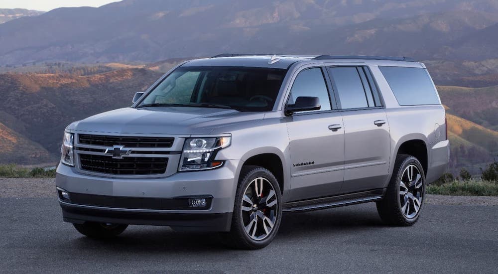 A silver 2020 Chevy Suburban RST is parked in front of mountains.